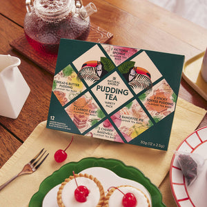 Box of Pudding Teas on a Dining Table with two Bakewell Cherry Tarts on a plate and a fork 