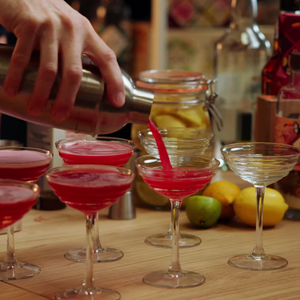 Hand Pouring Natural & Noble Cocktail Kit From Shaker Into Coupe Glasses