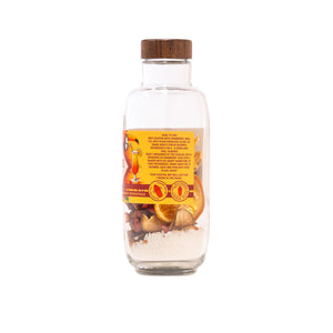 Clear glass bottle with wooden cap containing tea mix on a white background