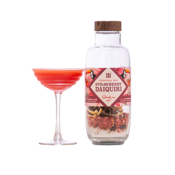 Bottle of strawberry daiquiri cocktail mix with a labeled glass filled with a red drink on a white background