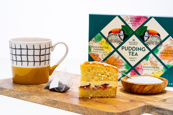 Tea packaging with a slice of cake and a mug on a wooden board