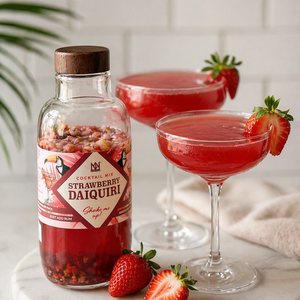 Two Strawberry Daiquiris Garnished with Fresh Strawberries, Alongside the Natural & Noble DIY Cocktail Kit